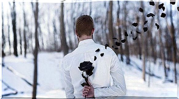 Man hiding black flower with petals flying