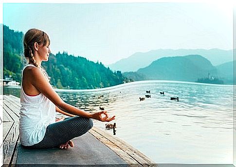 woman meditating in front of lake