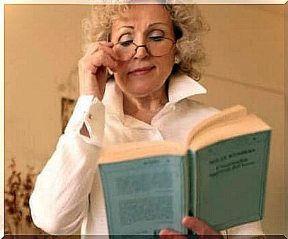 Woman reading book holding glasses