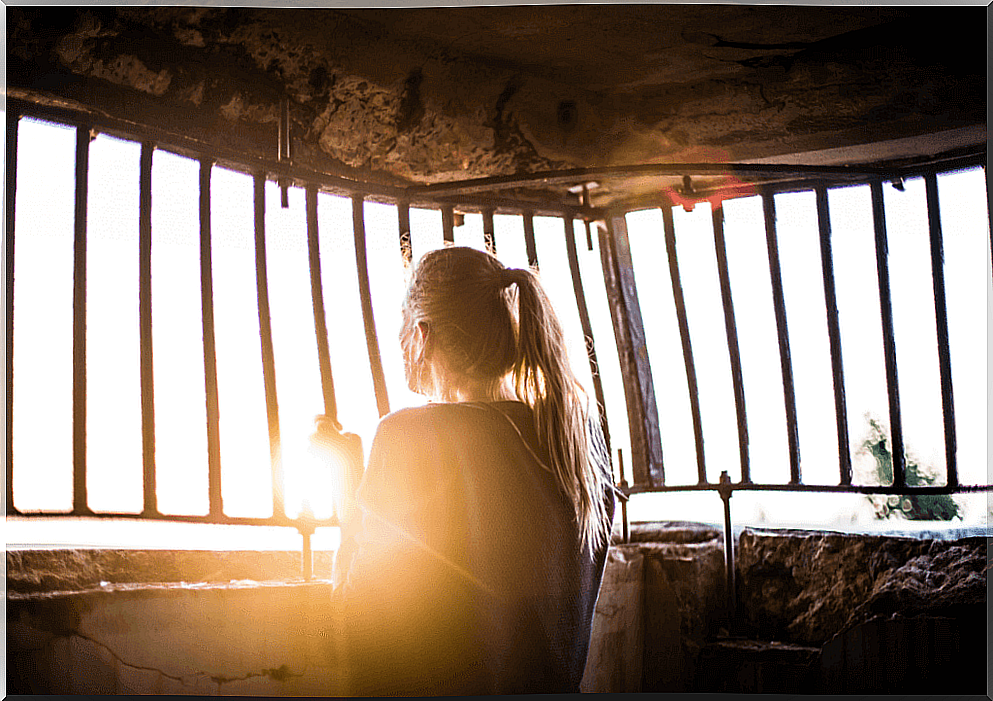 Woman looking through barred window.