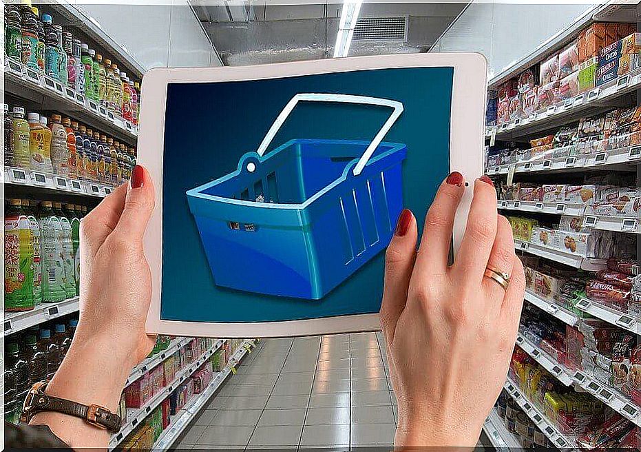 Woman with tablet with supermarket cart.